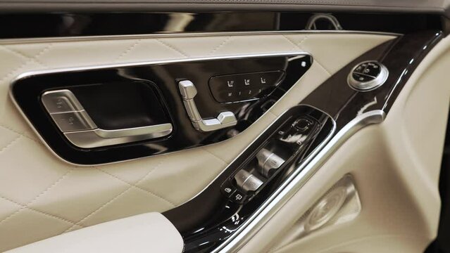 Close-up of the car door with leather trim and black glossy inserts, electric seat adjustment and power windows.