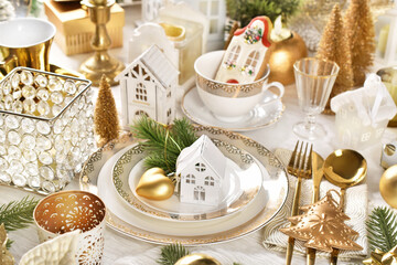 Christmas table setting with house theme decors in white and gold colors