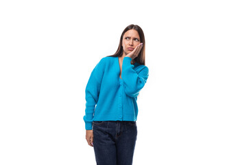 young stylish brunette lady dressed in a blue V-neck sweater is sad on a white background with copy space