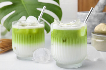 Glasses of tasty iced matcha latte on white tiled table