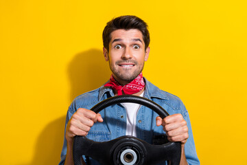 Photo portrait of attractive young man bite lips nervous hold rudder wear trendy jeans clothes isolated on yellow color background