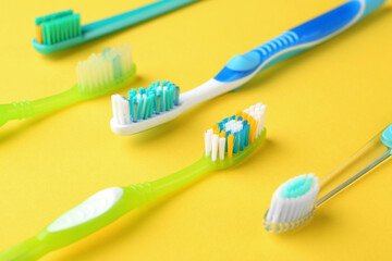 Many different toothbrushes on yellow background, closeup