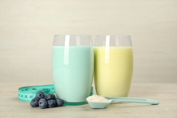 Tasty shakes with blueberries, measuring tape and powder on wooden table. Weight loss