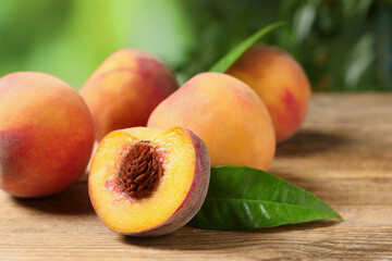 Cut and whole fresh ripe peaches on wooden table against blurred background, closeup. Space for text