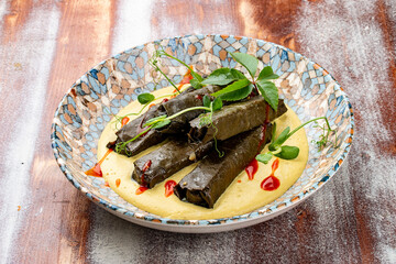 Dolma in grape leaves with lamb on mushroom julienne. Haute cuisine. On a wooden background.