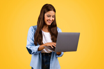 Happy pretty european teenager student lady typing on computer
