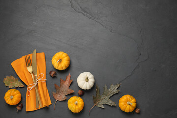 Cutlery, napkin and autumn decoration on black background, flat lay with space for text. Table...