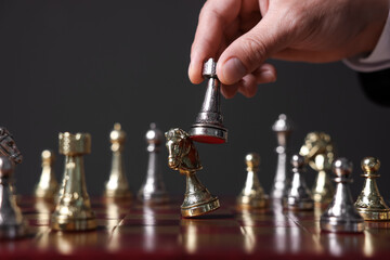 Man with rook game piece playing chess at board against dark background, closeup