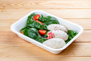 Steamed cutlets made of three kinds of meat. Healthy diet. Takeaway food. Eco packaging. On a wooden background.