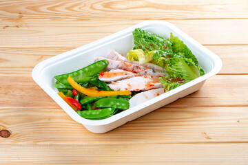 Turkey filet with fresh vegetables. Healthy diet. Takeaway food. Eco packaging. On a wooden background.