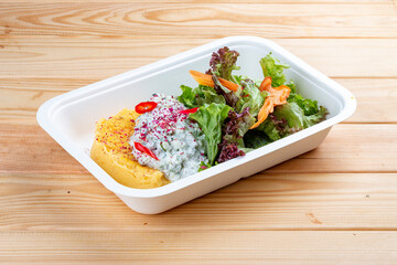 Polenta with tartare and avocado. Healthy diet. Takeaway food. Ecological packaging. On a wooden background.