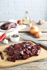 Cut raw beef liver and products on wooden table, space for text