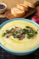 Bowl of tasty cream soup with mushrooms, green onions and dill on table, closeup
