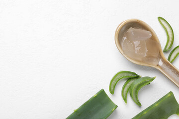 Aloe vera gel in spoon and slices of plant on white background, flat lay. Space for text