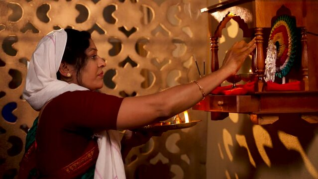 Indian traditional woman offering aarthi to god infront of mandapam during monring rituals - concept of tranquility, religious beliefs and custom rituals