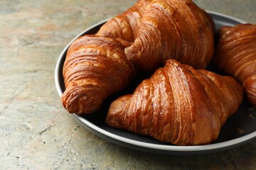 Delicious fresh croissants on grey textured table, closeup