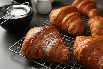 Delicious fresh croissants with powdered sugar on grey table, closeup