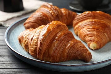 Delicious fresh croissants on black wooden table, closeup