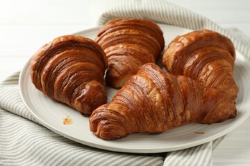 Plate with tasty croissants on white table, closeup