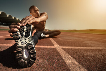 Naklejka premium Man, shoes and stretching leg on ground, sunset and fitness for health, sports and performance. Black male person, athlete and warmup on track, workout and commitment or ready, train and outdoors