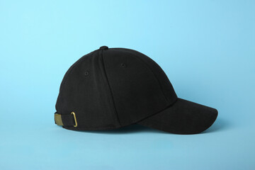 Stylish black baseball cap on light blue background