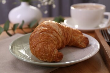 Tasty croissant served on wooden table, closeup