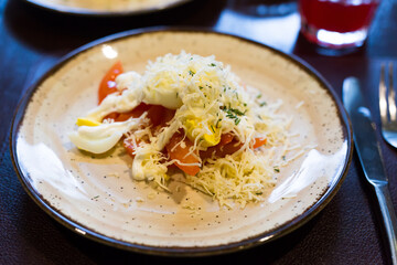 Mix of tomatoes, cheese, eggs with mayonnaise on a plate in a restaurant
