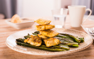 Fried chicken breast pieces with asparagus on white plate