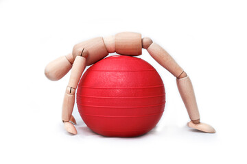 Wooden artist's mannequin is performing a stretching exercise over a red gym ball