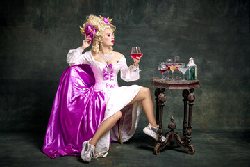 Charming queen, aristocratic medieval person in old-fashioned dress and modern shoes sitting...