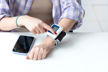 Close-up of young woman measuring pulse and blood pressure with wrist tonometer. Health care and...