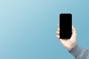 A man hand holding smart phone or mobile phone with blank screen on blue background. Service rating, satisfaction, customer experience concept