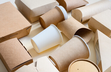 Lots of disposable paper tableware and packaging. Side view. Selective focus on white disposable paper cup. Eco-friendly packaging