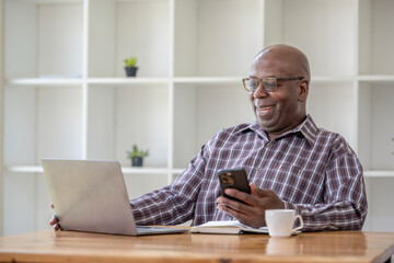 Senior black man talking on the phone and using at the laptop,  video call recommend and consult.