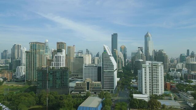 Aerial view of skyscraper buildings with green trees in Lumpini Park, Sathorn district, Bangkok Downtown Skyline. Thailand.