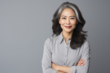 Studio portrait of well dressed mature Asian woman in front of grey background