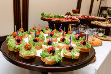 Canapes with olives, tomatoes and lettuce are served as an appetizer on the buffet table