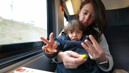 Mother teaching son to count while traveling by train commute. Attentive parent homeschooling her...