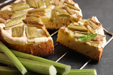 Freshly baked rhubarb pie and stalks on black table, closeup