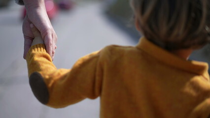Mother and child holding hands together walking forward outdoors