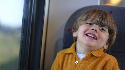 One happy little boy passenger child on train seat smiling and laughing while traveling