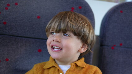 One happy little boy passenger child on train seat smiling and laughing while traveling