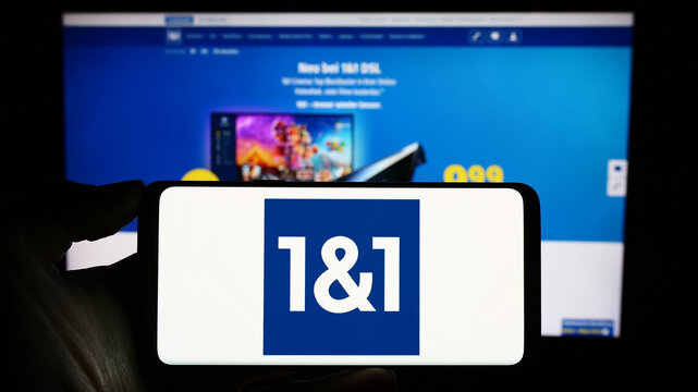 Stuttgart, Germany - 11-15-2023: Person holding cellphone with logo of German company 1und1 Telecommunication SE in front of business webpage. Focus on phone display.