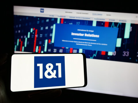 Stuttgart, Germany - 11-15-2023: Person holding mobile phone with logo of German company 1und1 Telecommunication SE in front of business web page. Focus on phone display.