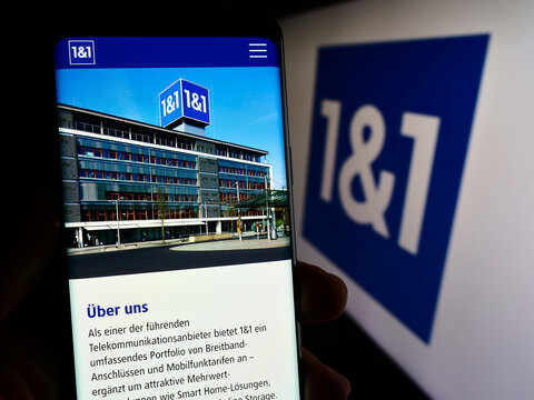 Stuttgart, Germany - 11-15-2023: Person holding smartphone with web page of German company 1und1 Telecommunication SE in front of business logo. Focus on center of phone display.