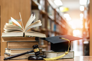 Law education, legal educational study, school for lawyer, legistration, litigation, judicial knowledge learning concept with court judge gavel and textbook with mortarboard on books in library - obrazy, fototapety, plakaty