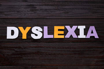 Word Dyslexia made of paper letters on dark wooden table, flat lay