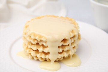 Tasty waffles with condensed milk on plate, closeup