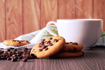 White cup with hot coffee and sweet cookies and raw coffee grain. Breakfast backgrounds theme
