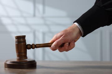 Judge with gavel at wooden table indoors, closeup